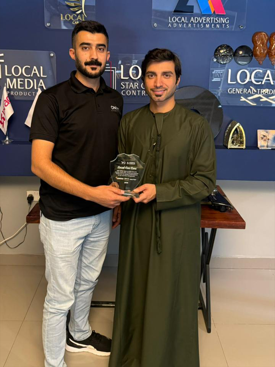 Al‑Rabiya sales representative presenting a reward to a car care partner for outstanding performance