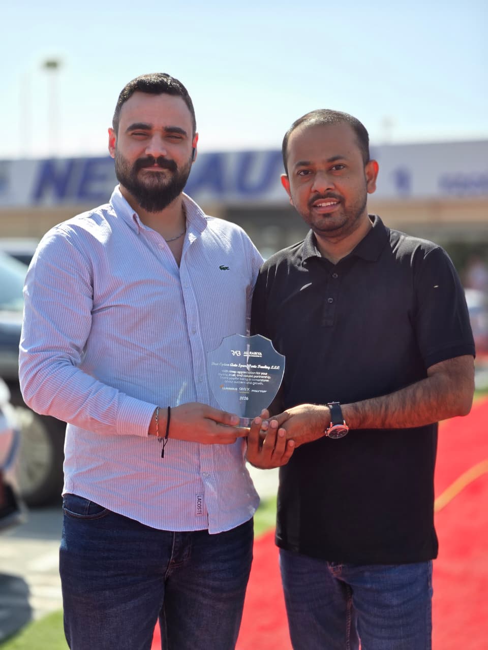 Al‑Rabiya sales representative presenting a reward to a car care partner for outstanding performance