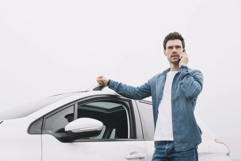A man-standing-near-car-talking-cellphone